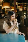 Жінка з напоєм сидить у кафе — стокове фото