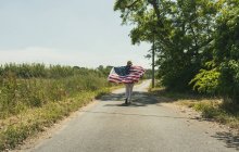 Femme marchant avec drapeau américain — Photo de stock