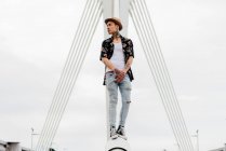 Hipster standing on railing of bridge — Stock Photo