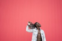 Homem americano africano com dispositivo de rádio vintage em fundo vermelho — Fotografia de Stock