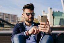Man relaxing with smartphone on seafront — Stock Photo