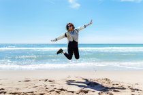 Жінка стрибає на піщаному пляжі — стокове фото