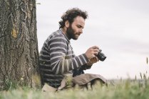 Fotoperiodista masculino sentado con cámara - foto de stock