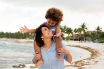Жінка з сином на плечах на пляжі — стокове фото