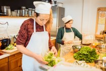 Жінки працюють з салатом на кухні — стокове фото