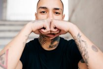 Hipster couvrant le visage avec des mains tatouées — Photo de stock
