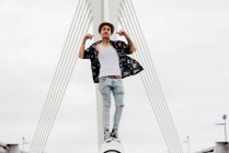 Hipster de pie sobre la barandilla del puente - foto de stock