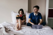 Paar benutzt Gadgets im Bett — Stockfoto