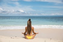 Woman in bikini meditating at ocean — Stock Photo