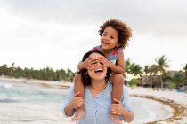 Жінка з сином на плечах на пляжі — стокове фото