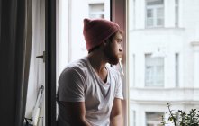 Nachdenklicher Mann sitzt auf Fensterbank — Stockfoto