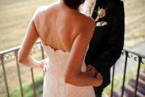Mano dello sposo irriconoscibile che abbraccia la sposa in abito bianco. — Foto stock