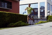 Веселий спортивний етнічний чоловік стрибає під час бігу в місті — стокове фото