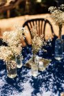 Маленькие белые деревенские цветы в бутылках вина на столе. — стоковое фото