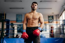 М'язистий чоловік в рукавичках, стоячи в спортзалі — стокове фото
