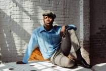 Стильний чорний чоловік сидить на підлозі — стокове фото
