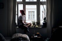 Seitenansicht eines nachdenklichen erwachsenen Mannes, der zu Hause in München auf der Witwenbank sitzt — Stockfoto