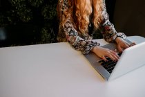 Redhead woman sitting and typing on laptop at table — Stock Photo