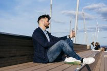 Man relaxing seafront with smartphone — Stock Photo