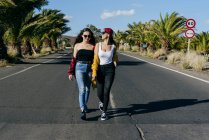Женщины идут по солнечной дороге — стоковое фото