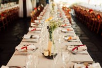 Vista para mesa de banquete longa com pratos servidos preparados para celebração. — Fotografia de Stock