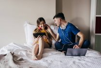 Couple partageant des gadgets et interagissant au lit — Photo de stock
