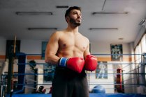 Homme musclé en gants debout dans la salle de gym — Photo de stock