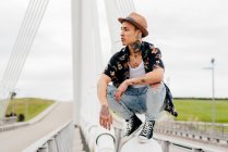 Hipster assis sur la rampe du pont — Photo de stock