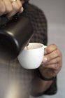 Mani di barista versando la crema in tazza — Foto stock