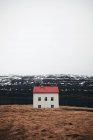 Pequena casa com telhado vermelho construído na colina nevada na Islândia — Fotografia de Stock