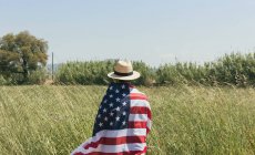 Hombre con sombrero envuelto bandera americana - foto de stock