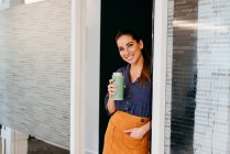 Улыбающаяся женщина с чашкой в офисе — стоковое фото