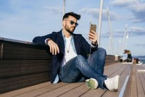 Мужчина расслабляющий смартфон на берегу моря — стоковое фото