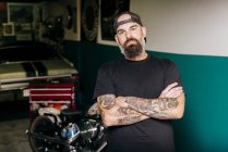 Tattooed mechanic standing in garage — Stock Photo