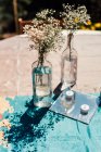 Kleine weiße, rustikale Blumen in Weinflaschen auf dem Tisch. — Stockfoto