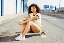 Adolescente assise sur skateboard — Photo de stock