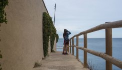 Chica de pie en barandilla en la orilla del mar - foto de stock