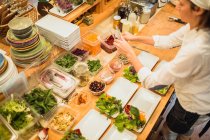 Assiettes de service femme avec salade — Photo de stock