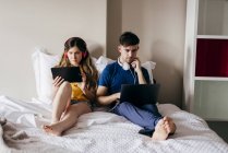 Casal usando gadgets na cama — Fotografia de Stock