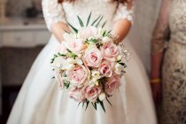 Cultivo novia irreconocible con hermoso ramo de flores de color rosa y blanco. - foto de stock