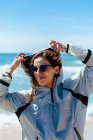 Donna in occhiali in piedi sulla riva del mare — Foto stock