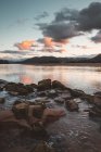 View of sea coastline with rocks in water on background of sunset dusk sky with fluffy clouds, Laida, Bizkaia — Stock Photo
