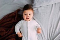 Curieux bébé garçon couché sur le lit — Photo de stock