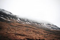 View to snowy hills with dry grass covering with mist in the morning in the Iceland — Stock Photo