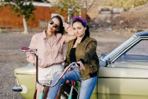 Frauen posieren vor grünem Auto — Stockfoto