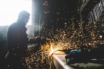 Uomo lavora con smerigliatrice taglio metallo. — Foto stock