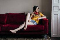 Женщина в наушниках сидит на диване — стоковое фото