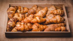 Mistura de croissants dourados em bandeja de madeira — Fotografia de Stock