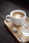 Cup of cappuccino and glass of water — Stock Photo