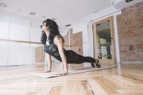 Donna che pratica yoga su tappetino in classe — Foto stock